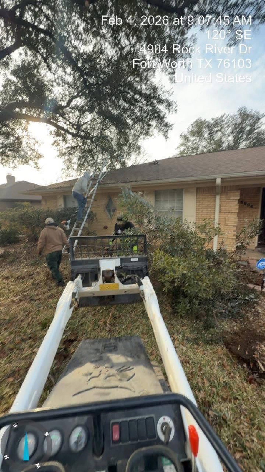 Crew clearing overgrowth off a Fort Worth house with a skid steer